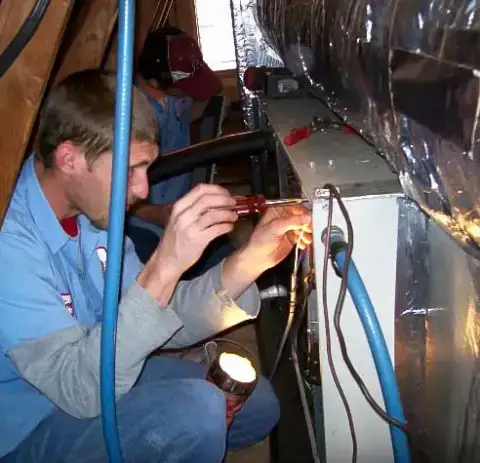 A technician from Norris Mechanical Shop works on a customer's furnace unit